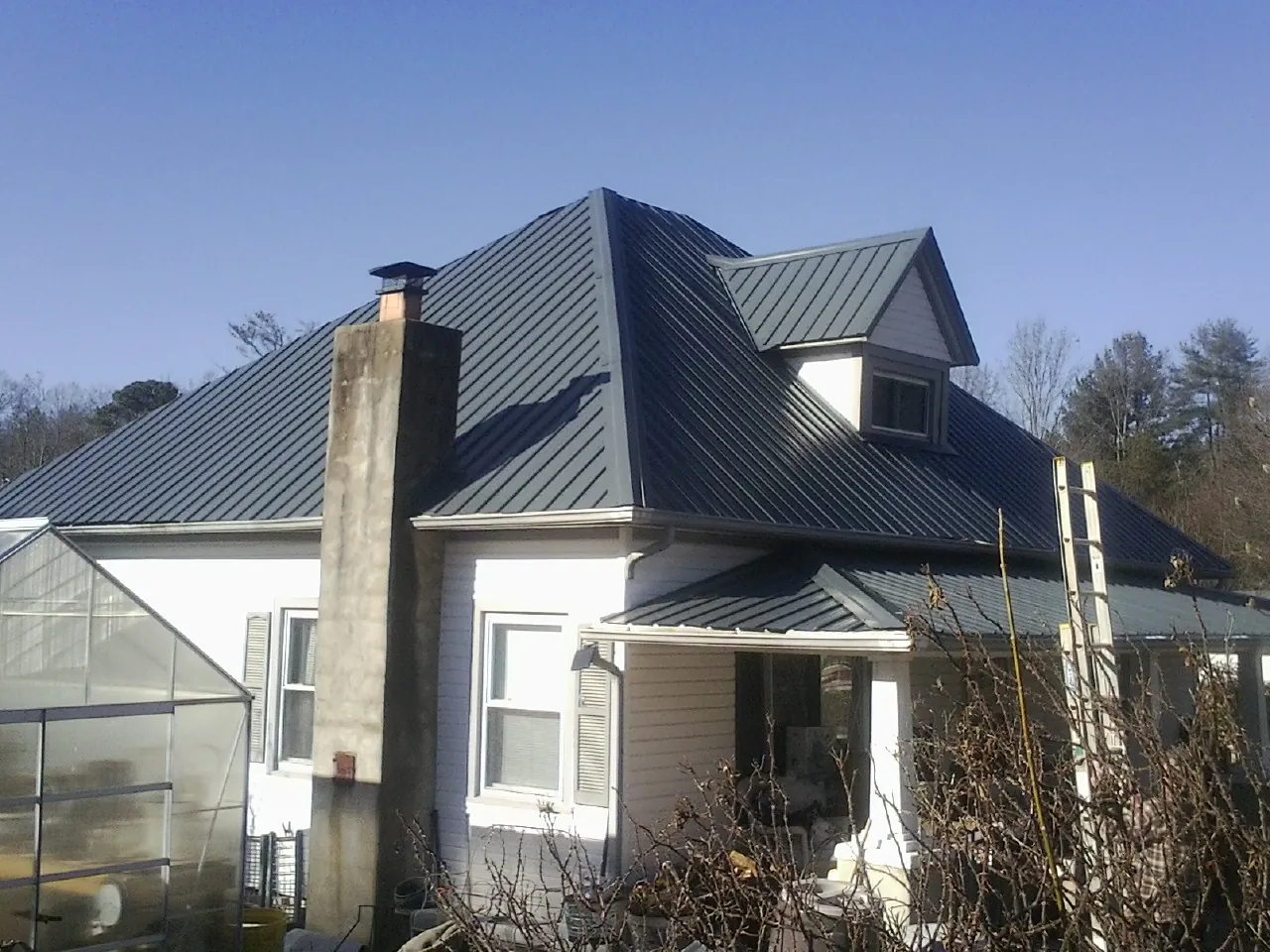 Dark blue standing seam metal roof on a white farmhouse with dormer — Slate & Tile Roof Repair by Roofing Brothers in Tremonton