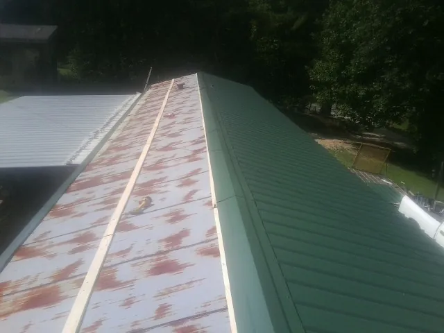 Old rusted panels beside newly installed green metal roofing — Wind Damage Roof Repair by Roofing Brothers in Tremonton