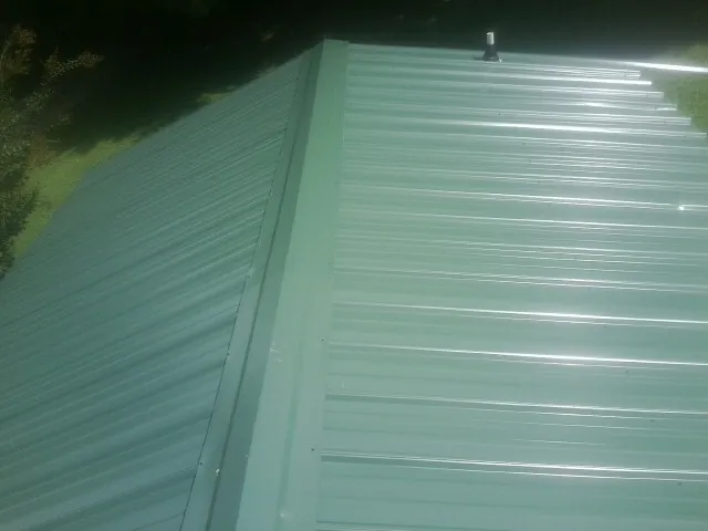 New green metal panels meeting at the ridge of a roof — Flat Roof Repair work by our crew in Tremonton