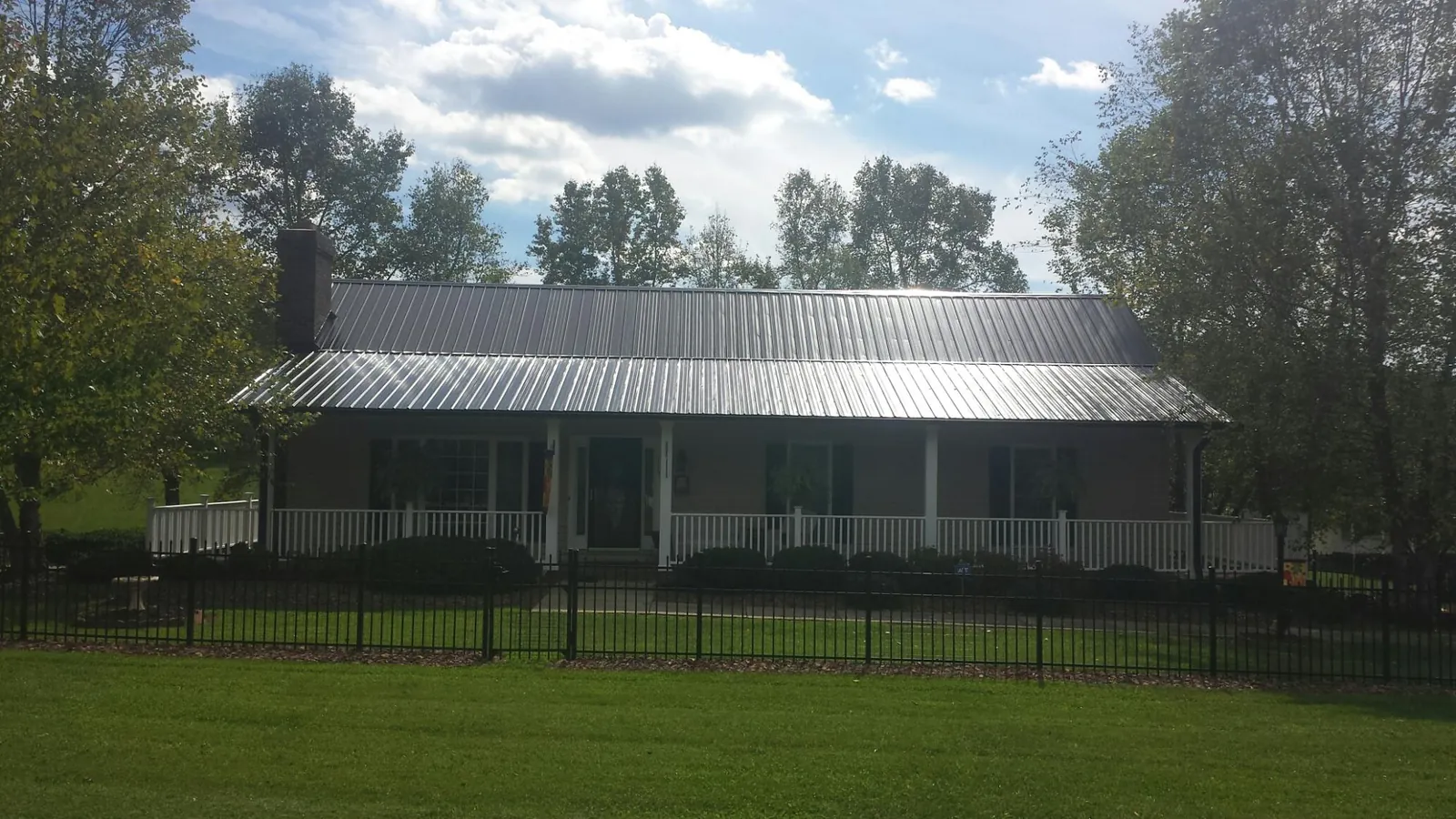 Gray metal roof on a brick ranch with a full width front porch — Gutter Guard Installation work by our crew in Tremonton