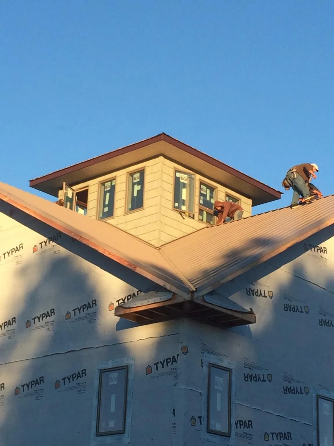 Roofers working around a rooftop cupola on a new metal roof at sunset — Roof Waterproofing in Tremonton by Roofing Brothers